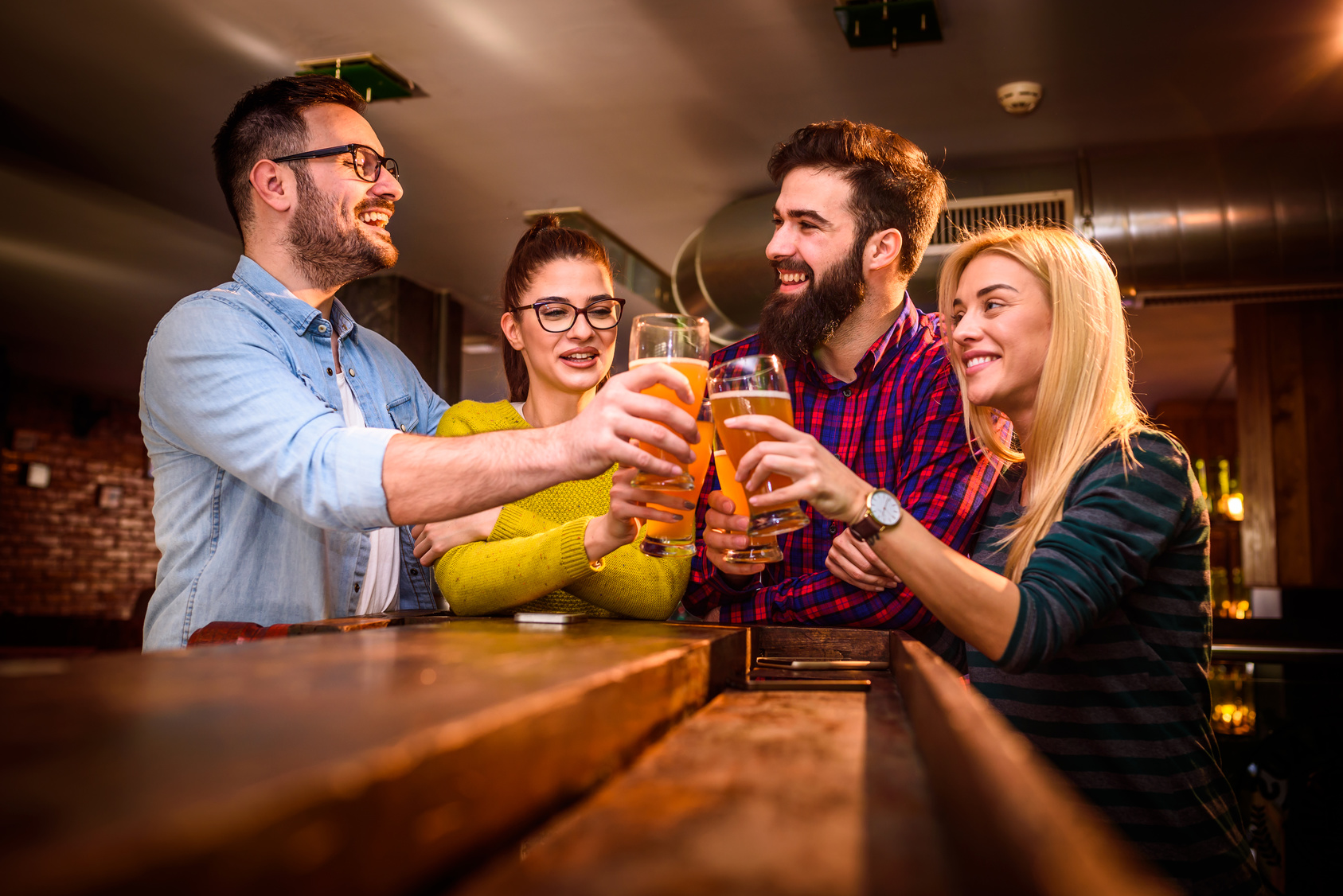 Group of young friends in bar drinking beer toasting